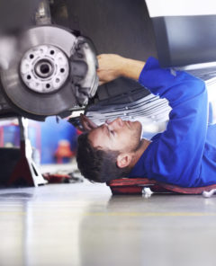 A car mechanic working on the underside of a car